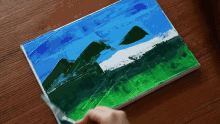 a person is painting a picture of mountains on a table
