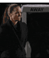 a woman is standing in front of a sign that says away .