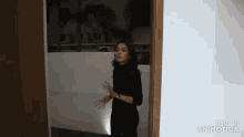 a woman in a black turtleneck sweater is standing in a dark room .