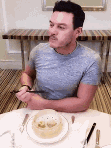 a man with a mustache is sitting at a table eating dim sum