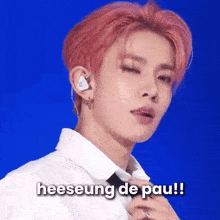 a young man with pink hair is wearing a white shirt and tie and says heeseung de pau !