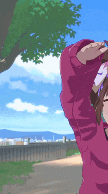 a girl in a pink sweater is standing in front of a fence