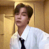 a young man in a white shirt and tie is standing in front of a door .