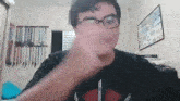 a man wearing glasses and a black shirt is making a funny face while looking at the camera .