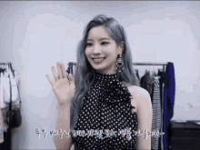 a woman with gray hair is wearing a black and white polka dot dress and waving