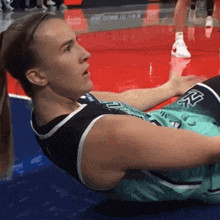 a female basketball player laying on the floor wearing a number 25 jersey