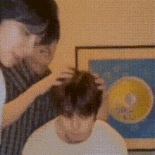a man is getting his hair cut by a man in a white shirt .