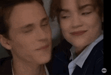 a man and a woman are smiling for a picture and looking at the camera .