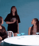 a woman wearing a shirt that says element is standing next to two other women at a table