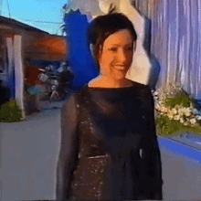 a woman in a black dress is smiling in front of a statue