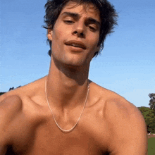 a shirtless man wearing a chain around his neck is smiling .