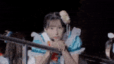 a girl in a blue and white dress with a flower in her hair leans on a railing