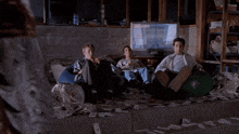 a group of people sitting on a pile of money watching a tv screen that says 00