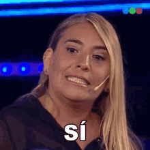 a woman with a microphone in her ear is smiling with the word si above her