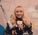 a woman is holding an umbrella and a microphone while being taped to a wall .