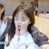 a little girl making a funny face with her hands on her face while wearing a jacket that says calvin klein