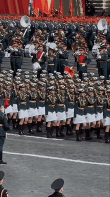 a parade of soldiers marching in a line with a band behind them