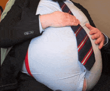 a man in a suit and tie holds his stomach