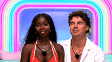 a man and a woman are posing for a picture in front of a colorful rainbow .