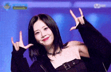 a woman is making a peace sign with her hands while wearing a black jacket .