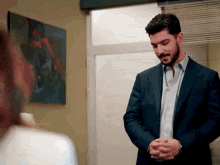 a man in a suit is standing in front of a painting