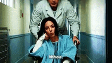 a man pushing a woman in a wheelchair down a hallway .