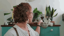 a woman stands in front of a table with plants and candles