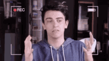 a young man is making a funny face while being recorded on a camera .