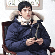 a man in a blue jacket is holding a pair of scissors