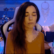 a woman with her eyes closed is wearing a brown shirt