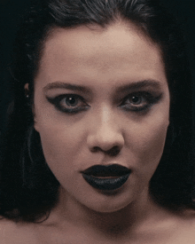 a close up of a woman 's face with black lipstick on