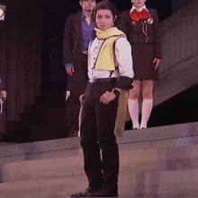 a man with a yellow scarf around his neck is standing on a stage with other people