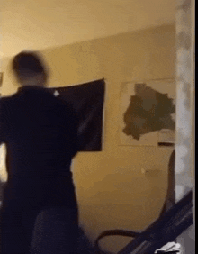 a man in a black shirt is holding a black flag in a living room .