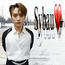 a young man is standing in front of a sign that says sybaum