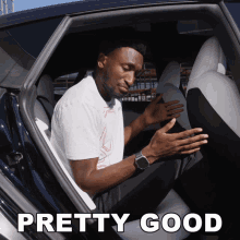 a man is sitting in the back seat of a car with the words pretty good behind him