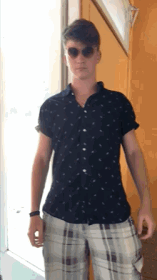 a man wearing plaid shorts and a black shirt