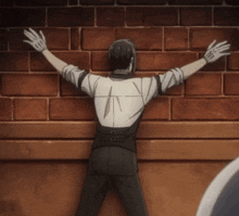 a man with his arms outstretched is leaning against a brick wall