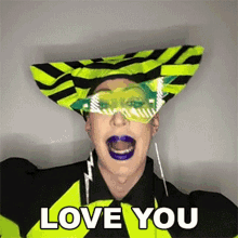 a woman wearing a striped hat and sunglasses is making a funny face and saying `` love you '' .
