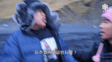a man wearing a blue jacket and a furry hat is talking to another man in a pink hat