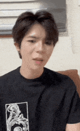 a young man wearing a black t-shirt with a floral design on the front is sticking his tongue out