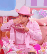 a man in a pink cowboy hat is eating food