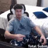 a man wearing headphones and pajamas is sitting in front of a computer monitor .