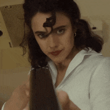 a woman in a white shirt holds a gun in her hand