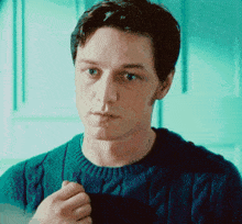 a man is wearing a blue sweater and looking at the camera