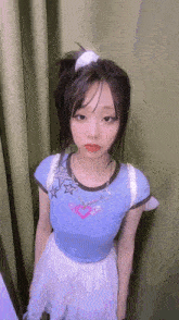a young girl wearing a blue shirt and a white skirt