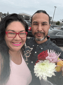a man and a woman are posing for a picture with flowers in their hands
