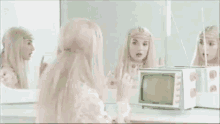 a woman in a white dress is sitting in front of a mirror looking at herself in the mirror .