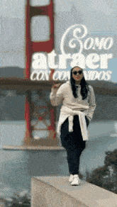 a woman standing on a wall in front of the golden gate bridge