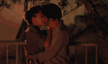 a man and woman are kissing under a tree at night