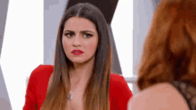 a woman in a red dress is making a funny face while looking at another woman .